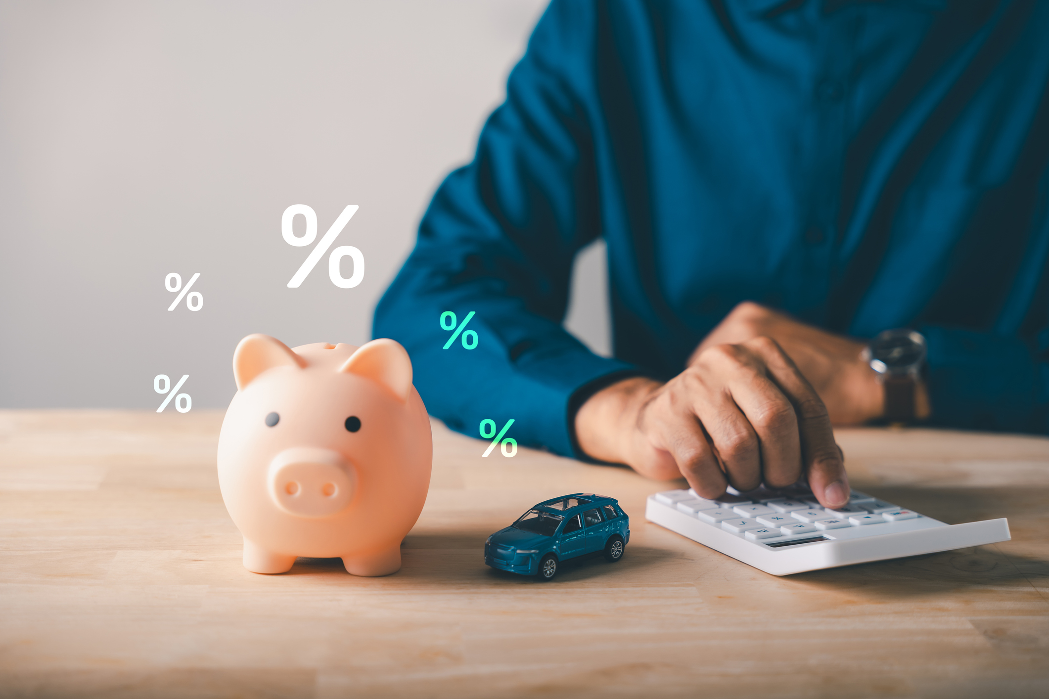 Man calculates car loan with piggy bank, saving money for auto insurance payments, bank offers safety for tax and budget planning, considering interest rates for vehicle purchase